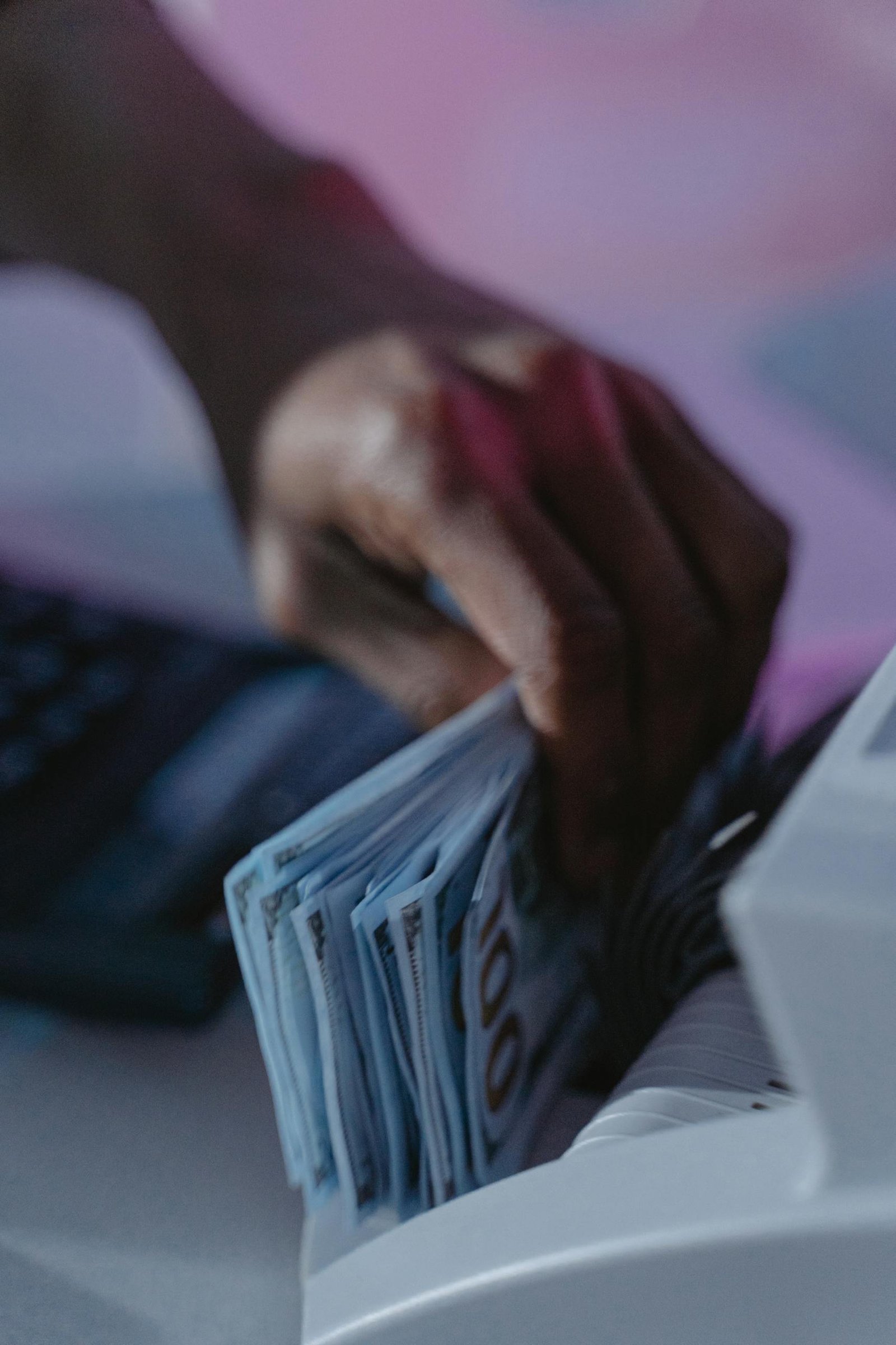 A close-up of a hand using a cash counter machine to sort bills.
