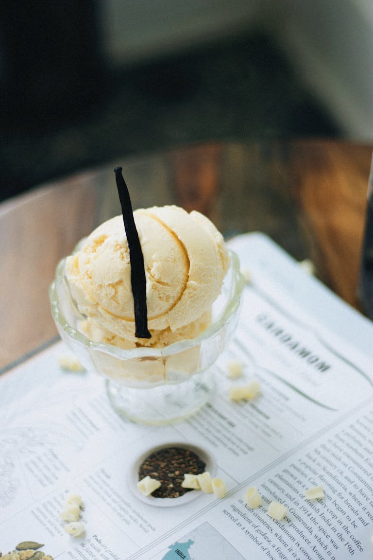Elegant presentation of vanilla ice cream with vanilla bean on paper background.