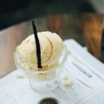 High-end food photography of a vanilla bean next to a scoop of ice cream