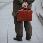 Man in coat holding a brown briefcase behind back