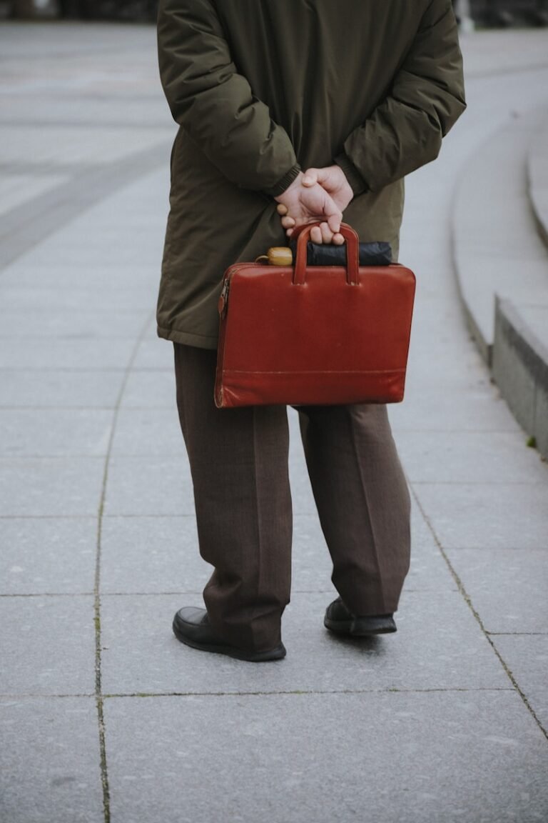 Man in coat holding a brown briefcase behind back