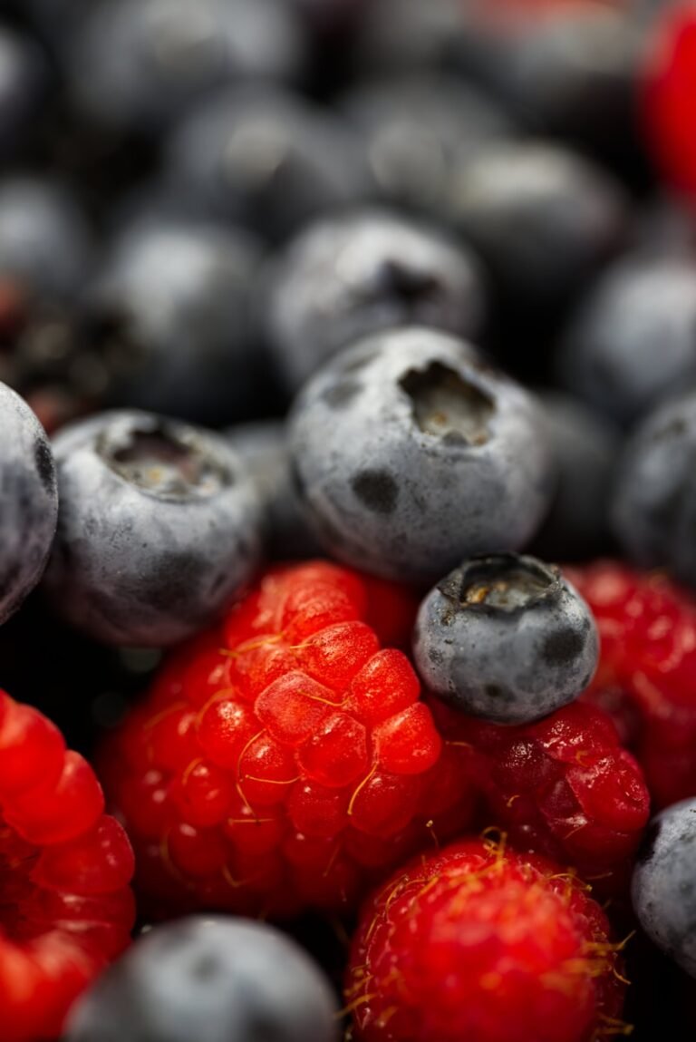 A pile of blueberries and raspberries sitting next to each other