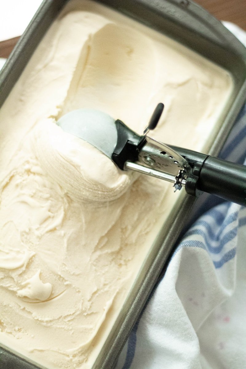 A close-up of smooth 3 ingredient ice cream being scooped out of a chilled container.